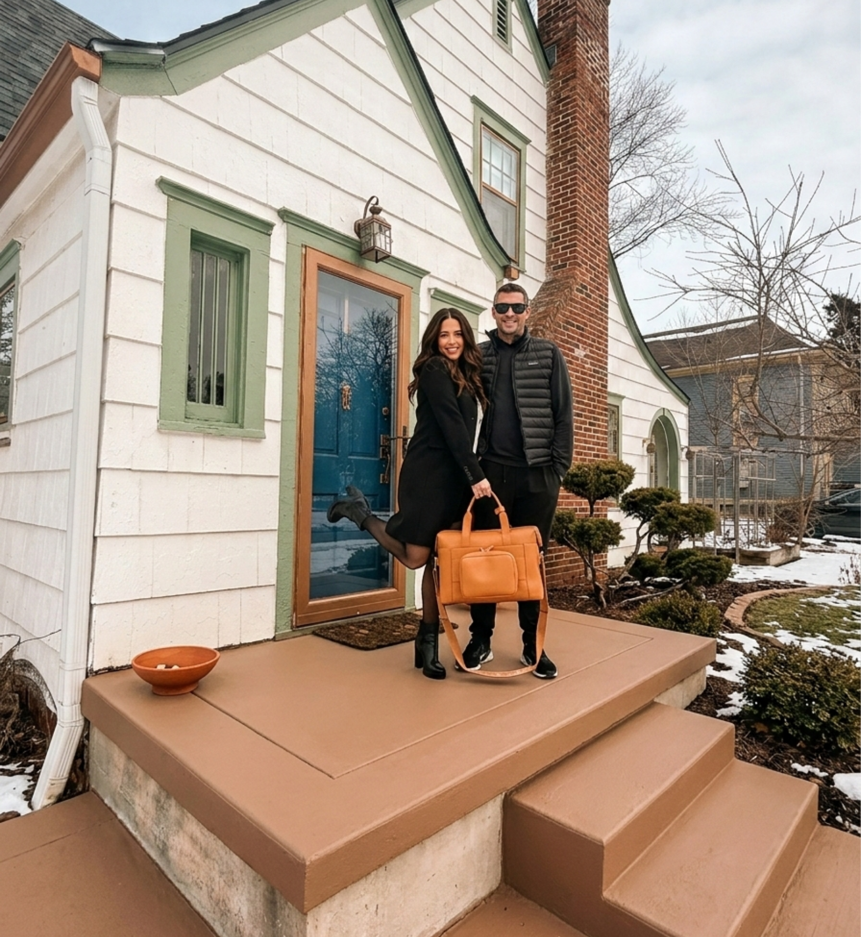 cute married couple with luggage on front step of short-term rental