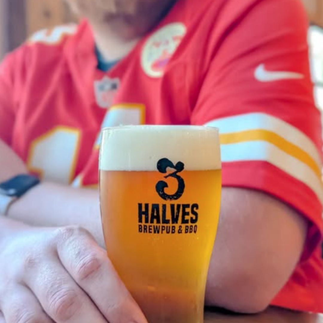 Sports fan ina Kansas City Chiefs shirts drinking a pint of beer