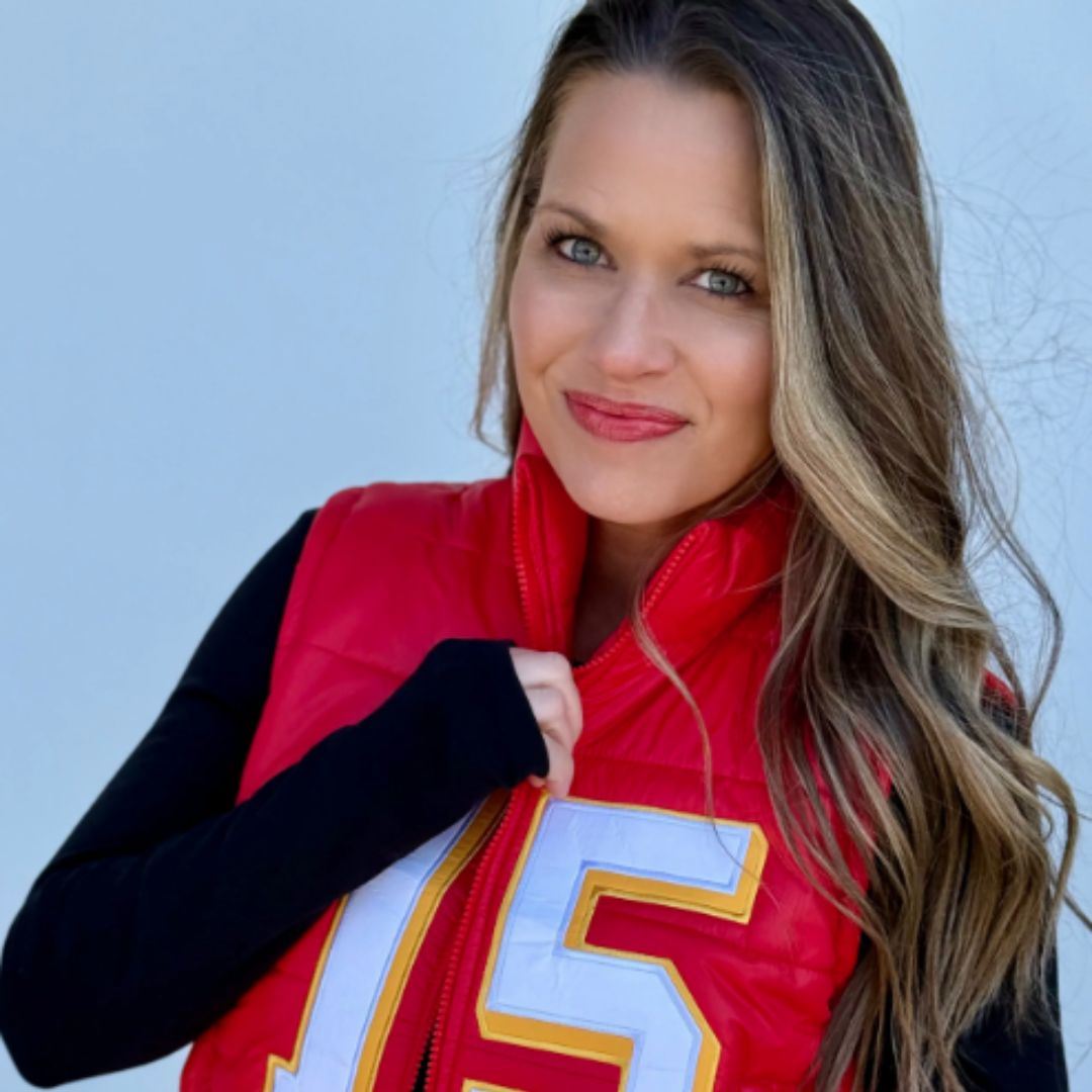 Brunette woman with black turtleneck and red vest with number 15 on chest