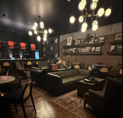 Button back green couch and orange latterns over bar in modern speakeasy